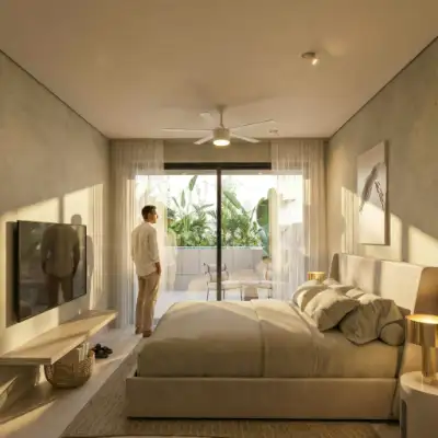 Bedroom with a wall-mounted TV, neutral bedding, and glass doors leading to an outdoor balcony at Atzaro Residences, Playa del Carmen