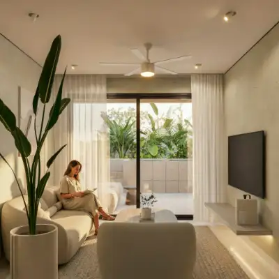 Living room with a large potted plant, neutral sofa, and sliding doors opening to a balcony at Atzaro Residences, Playa del Carmen