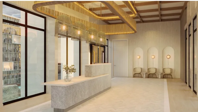 Pasillo de lobby con paredes de vidrio y luz natural en torre wellness BLAS en Puerto Cancún
