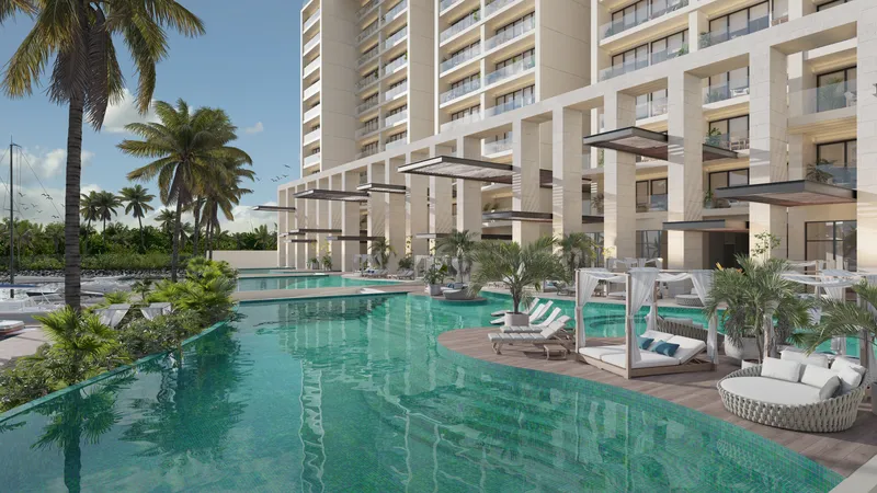 Alberca con palmeras y lounge de torre en exterior de residencia wellness BLAS en Puerto Cancún