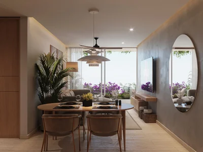 Comedor con espejo ovalado y materiales naturales en residencia serena Idilik en Playa del Carmen