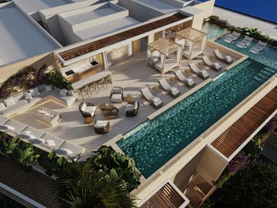 Vista aérea de alberca en azotea con camastros y alrededores tropicales en Idilik en Playa del Carmen