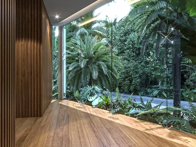 Terraza de madera con vistas a la jungla y barandales de vidrio en exterior de residencia wellness Idilik