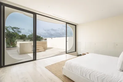Bedroom with arched window and jungle view at Mistiq Villas, Tulum