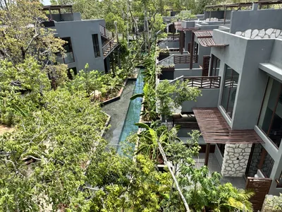 Elevated walkways connecting stone villas above river-style pool channels at Siwa Elevé in Tulum