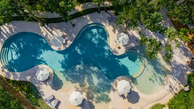 Vista aérea de alberca de forma libre en The Village Resort & Residences en Corasol, Playa del Carmen
