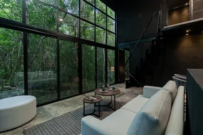 Loft-style living area with soaking tub and glass walls overlooking the jungle at Tree60 sustainable villa, Tulum