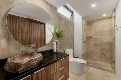 Bathroom with round mirror and wood accents at Xalet Tulum